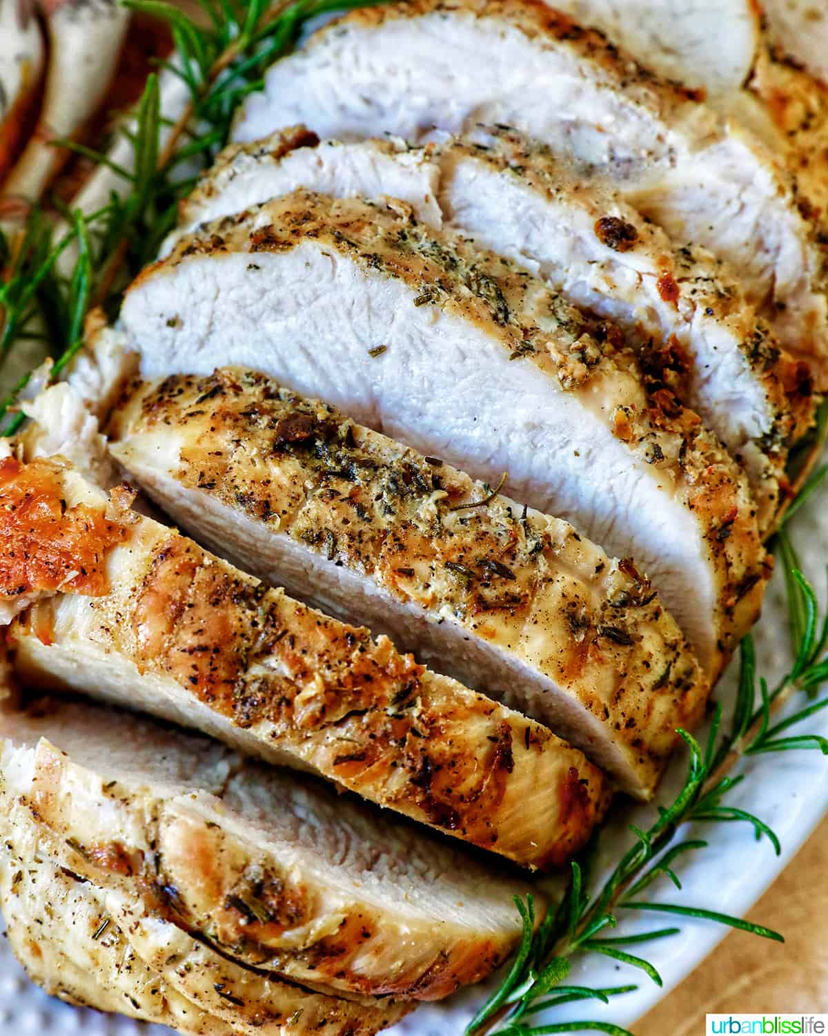sliced turkey breast with rosemary sprigs on a plate.