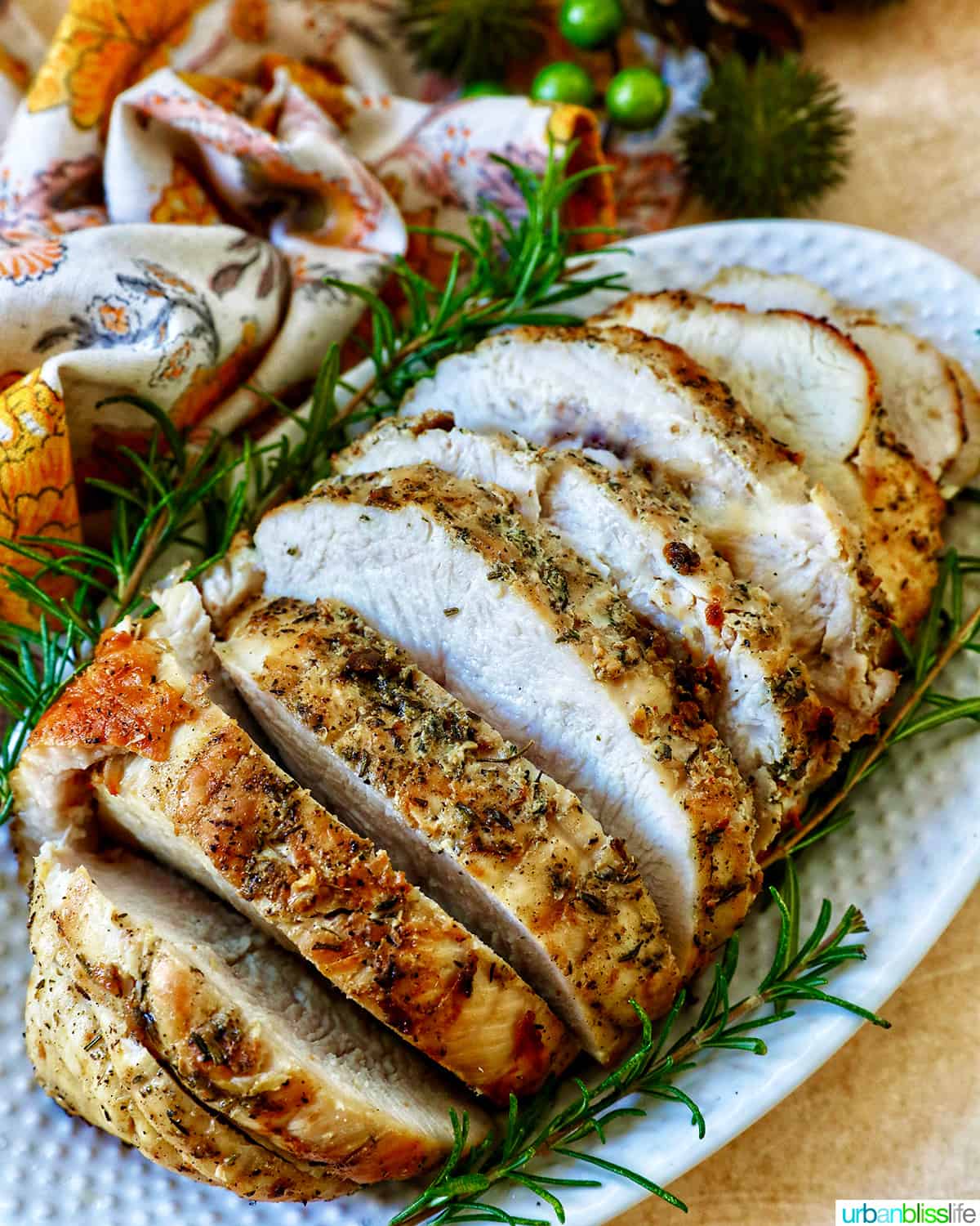sliced turkey breast with rosemary sprigs on a plate.