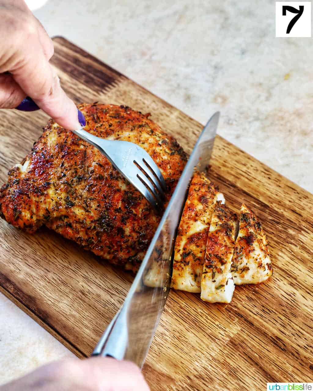 fork and knife slicing into a cooked turkey tenderloin on wood cutting board.