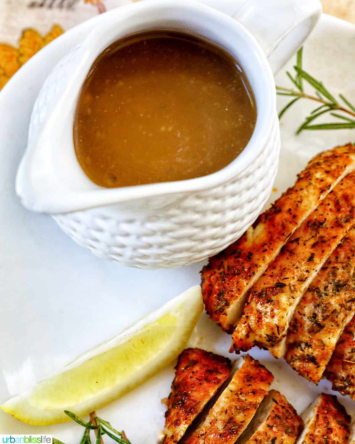 turkey gravy in a gravy boat on a plate with sliced turkey tenderloin.