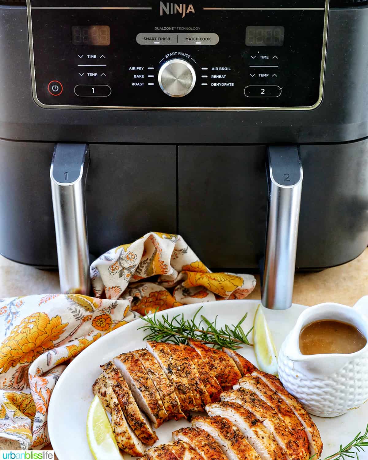 ninja dual air fryer with a plate of sliced turkey tenderloin and gravy in front of it.