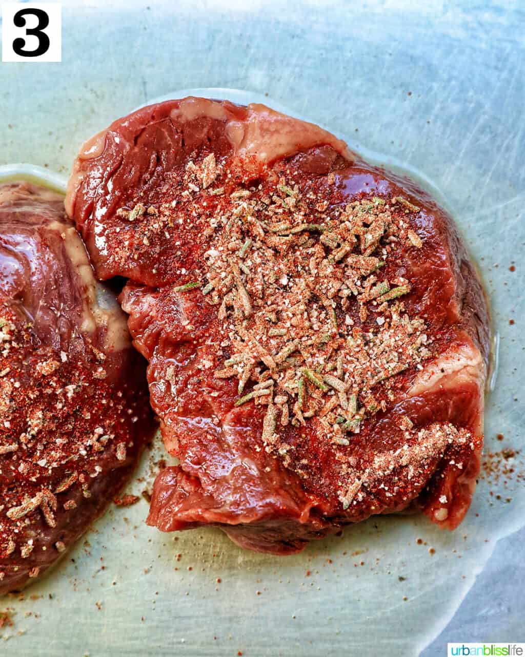 raw filet mignon with seasoning on top.