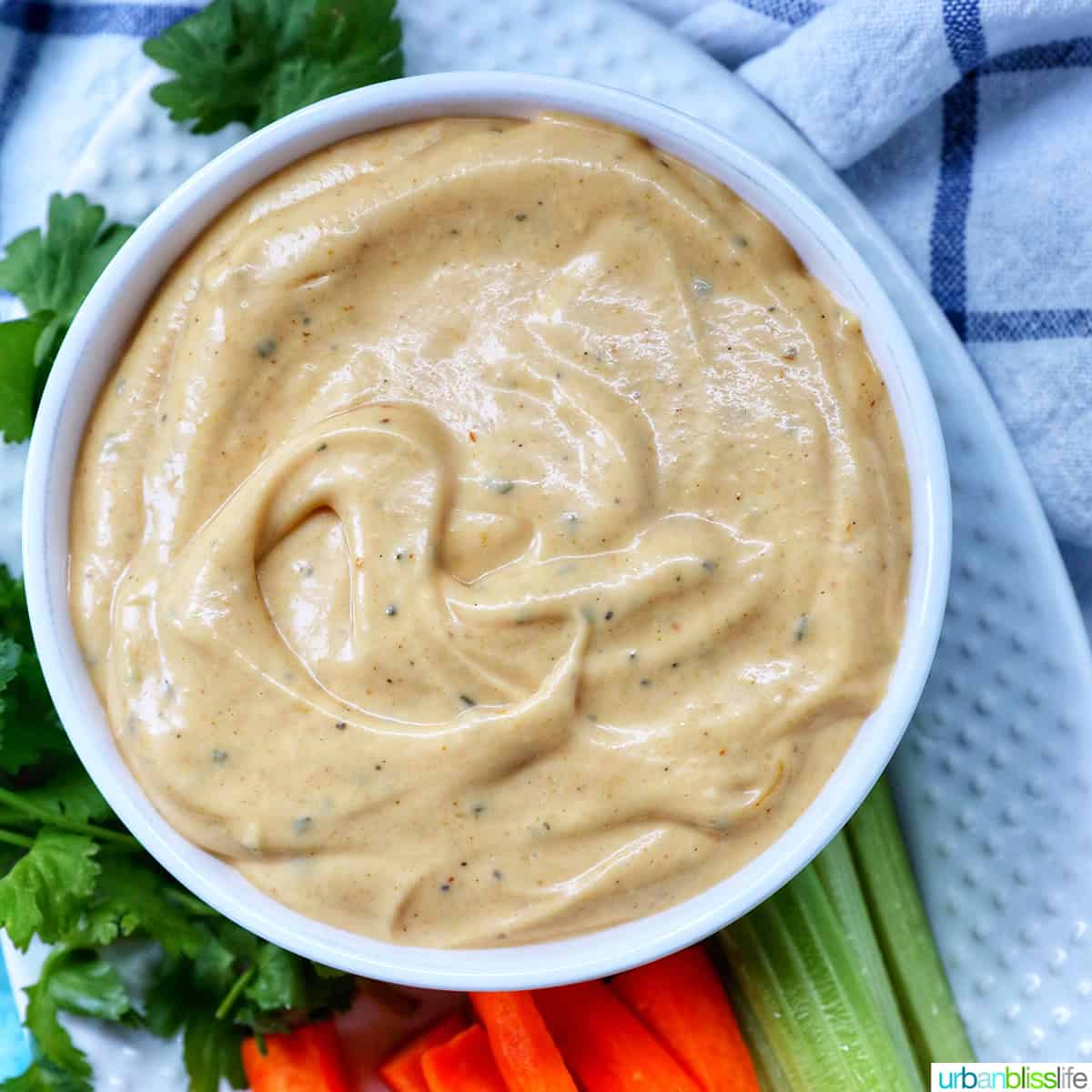 bowl of bowl of buffalo ranch sauce with a side of carrot sticks and more celery sticks.