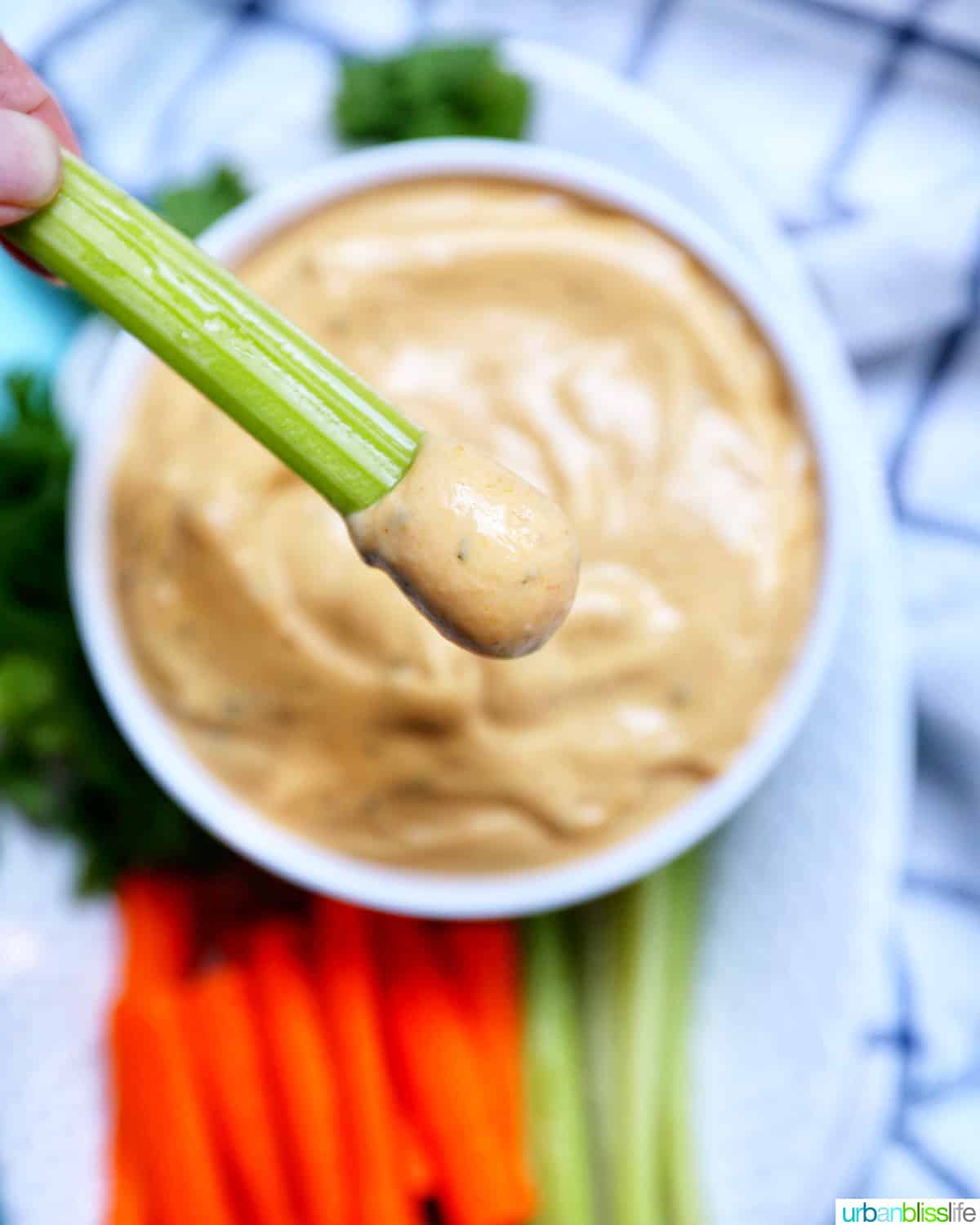 celery stick dipped into buffalo ranch sauce with a side of carrot sticks and more celery sticks.