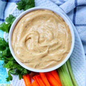 bowl of buffalo ranch sauce with a side of carrot sticks and more celery sticks.