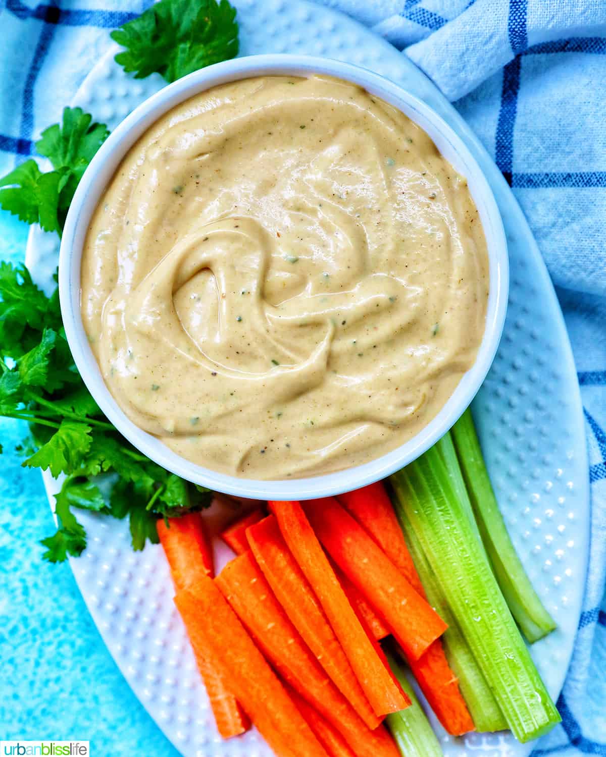 bowl of  buffalo ranch sauce with a side of carrot sticks and more celery sticks.