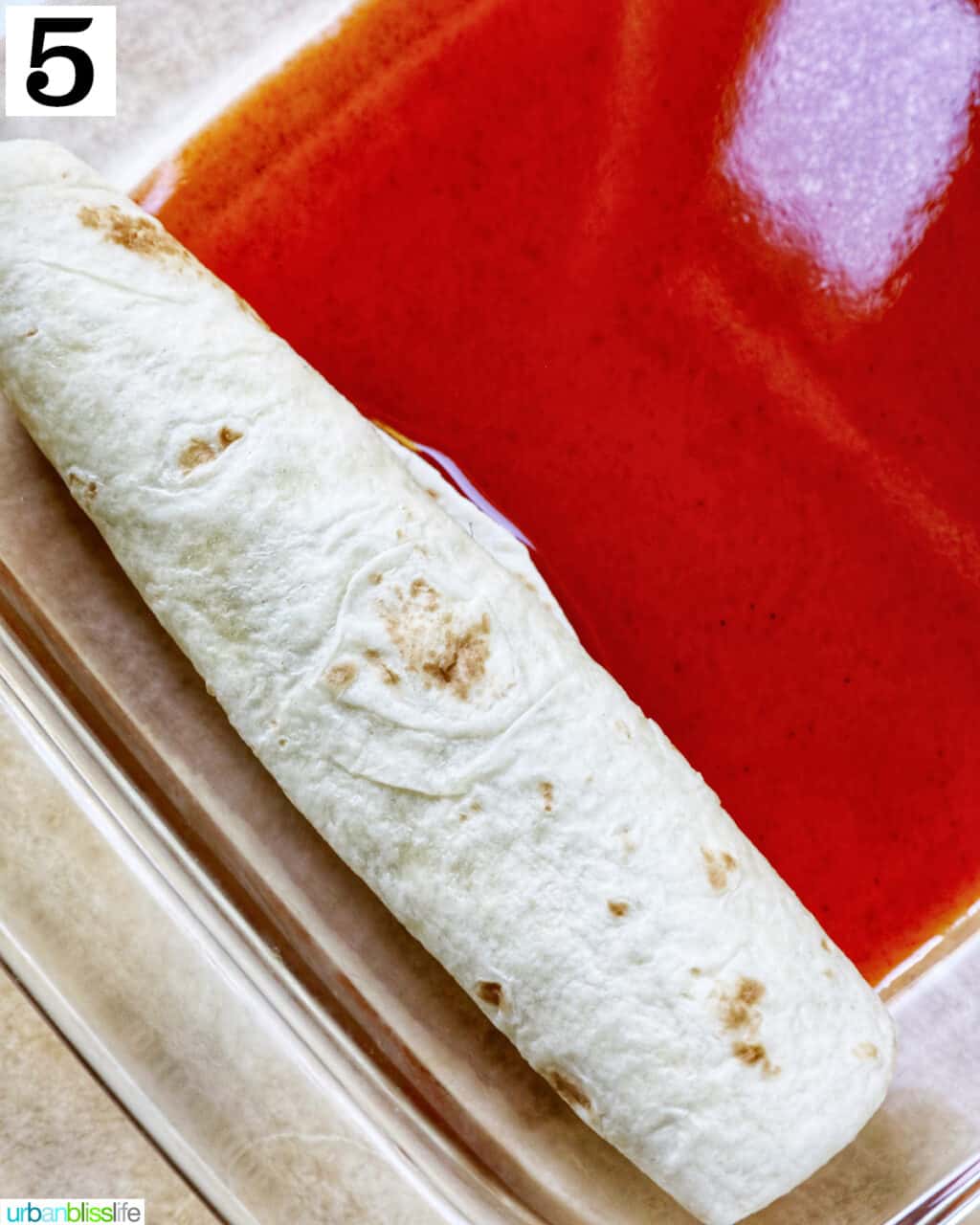 rolled flour tortilla enchiladas in a glass baking dish.