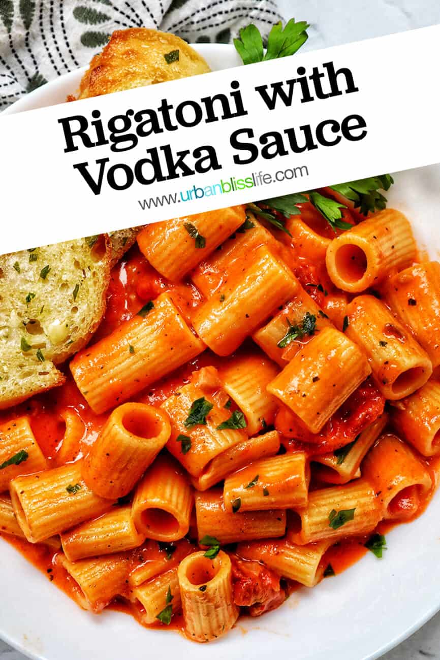 white bowl with rigatoni with vodka sauce and side of garlic bread and parsley with title text.