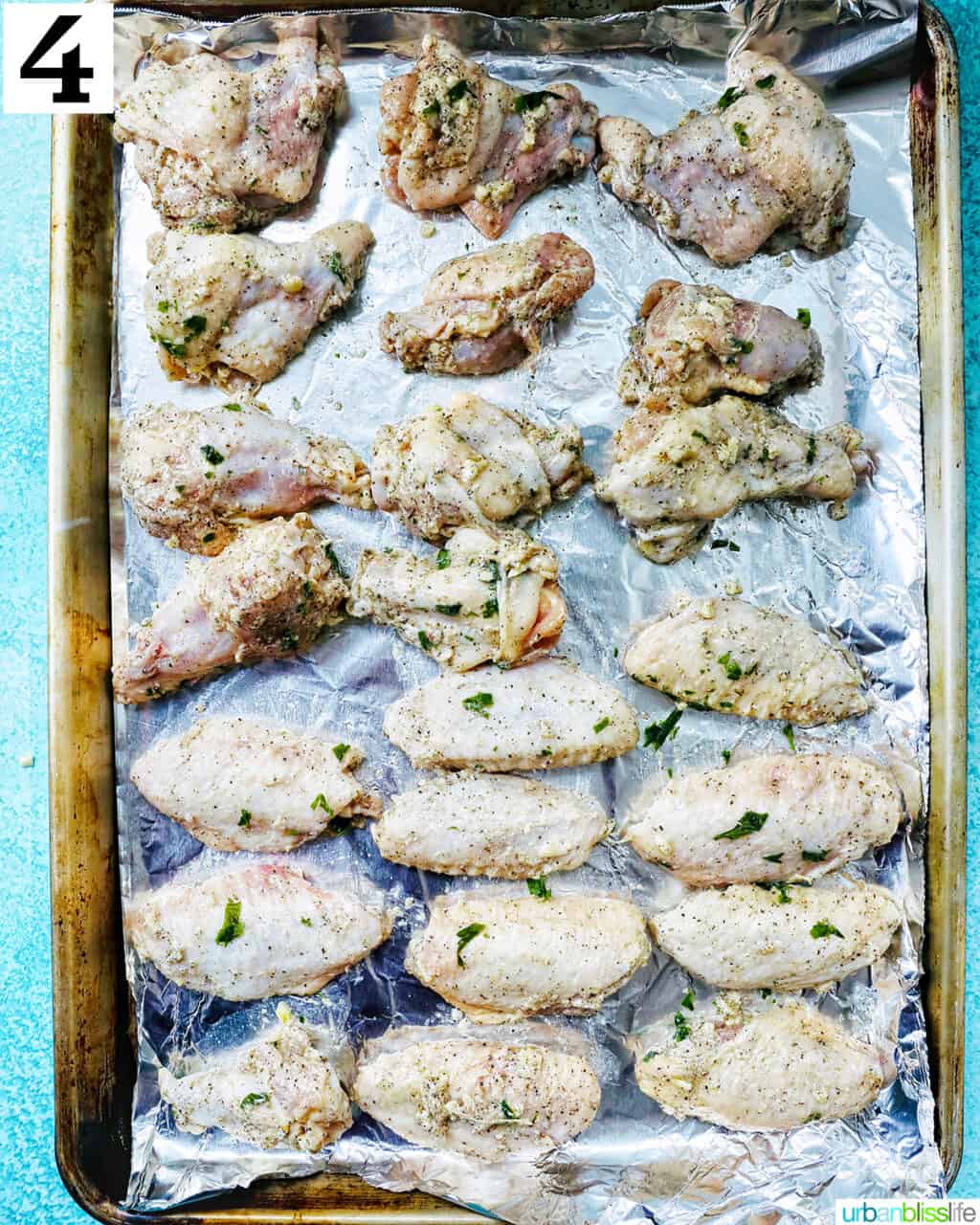 chicken wings in rows on aluminum foil on a baking sheet.