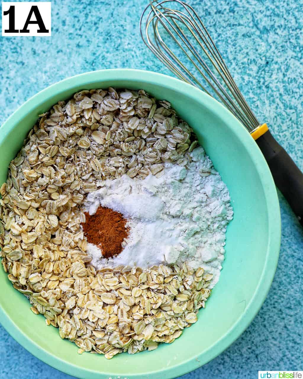 dry ingredients for cookie batter in a green bowl with whisk.