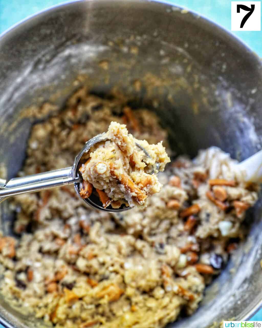 cookie scoop full of cookie dough over a stand mixer bowl full of cookie dough.