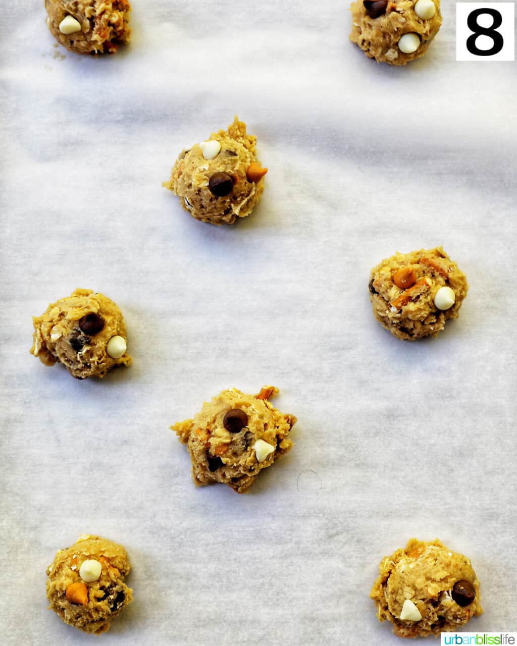cookie dough balls on parchment paper on a baking sheet.