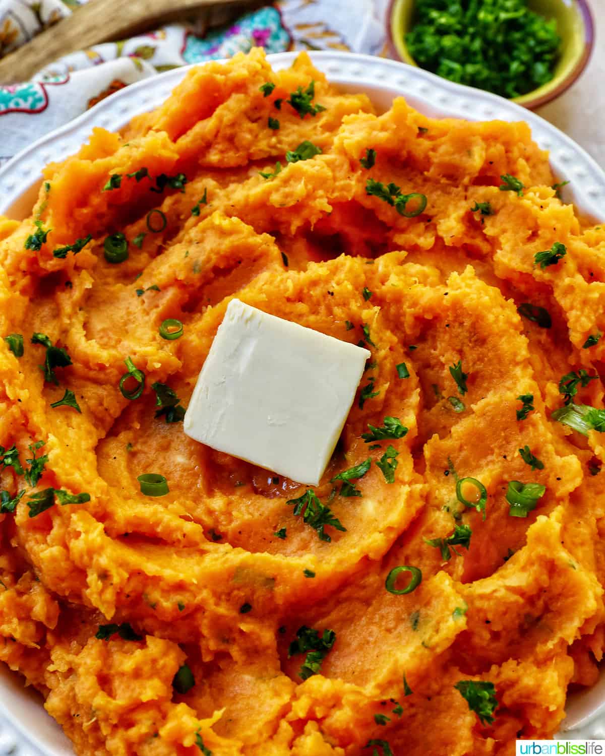 bowl of whipped sweet potatoes and a pat of butter with fresh herbs.