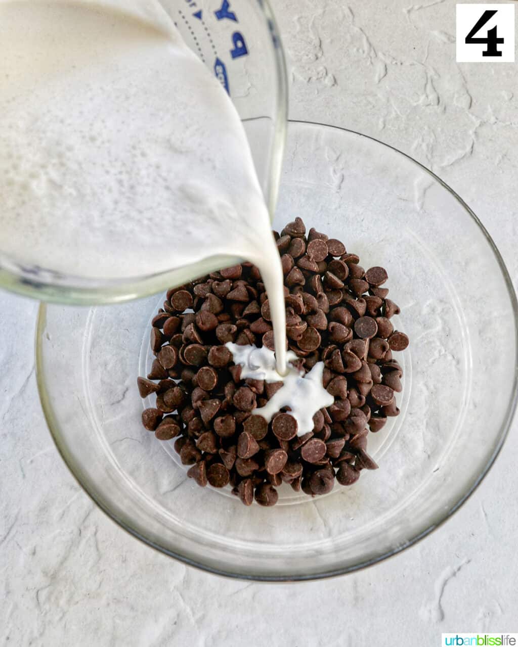 pouring cream over a glass bowl with chocolate chips.
