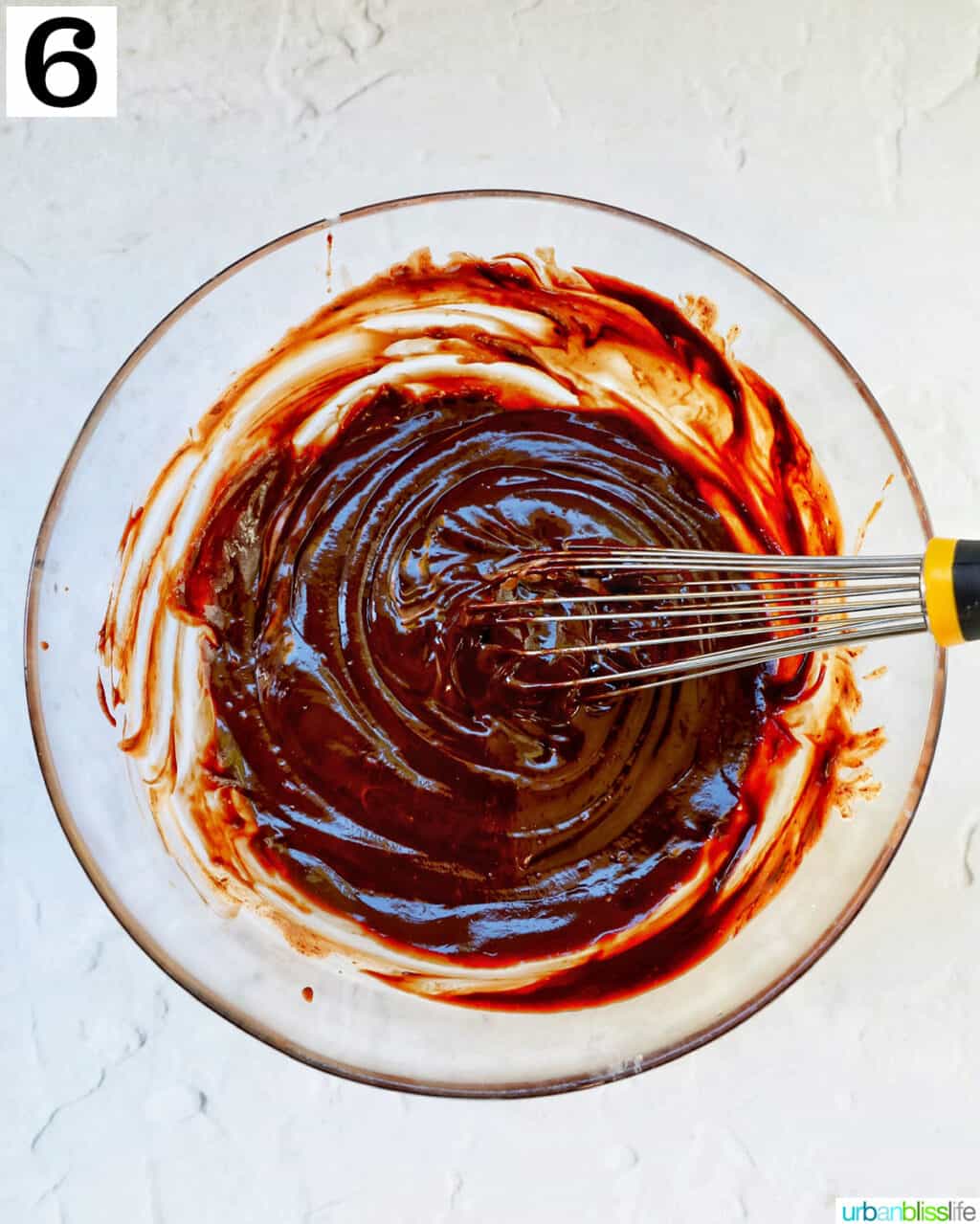 whisking chocolate in a glass bowl.