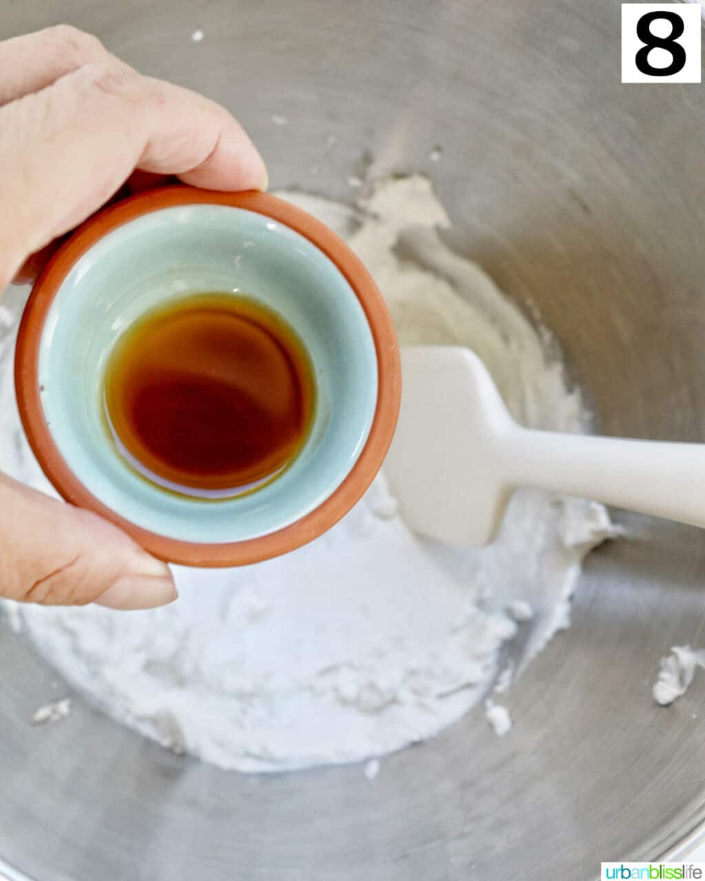 hand holding bowl of vanilla over whipped cream. 
