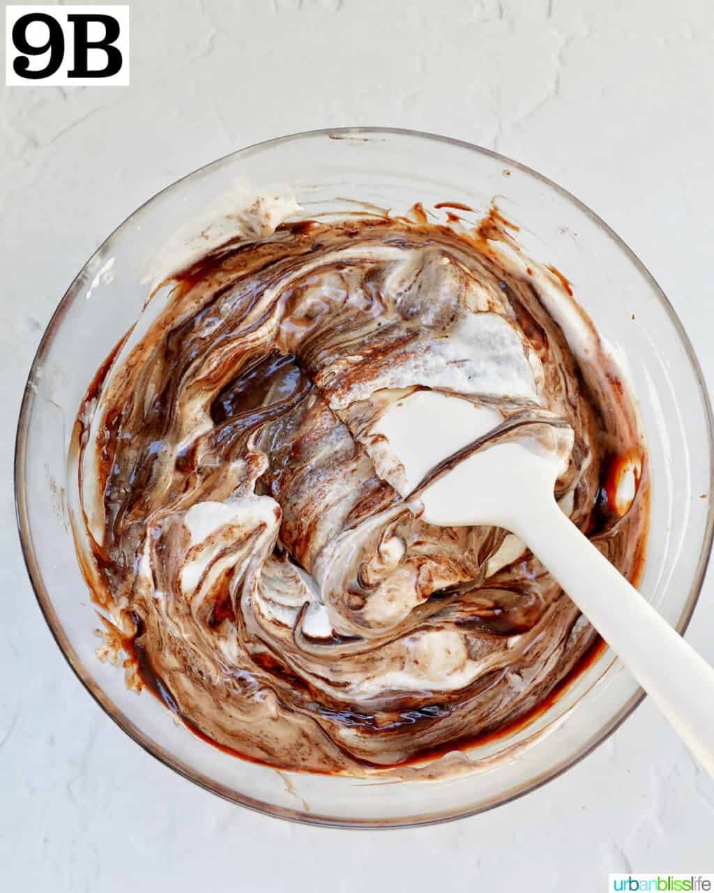folding whipped cream into chocolate in a glass bowl.