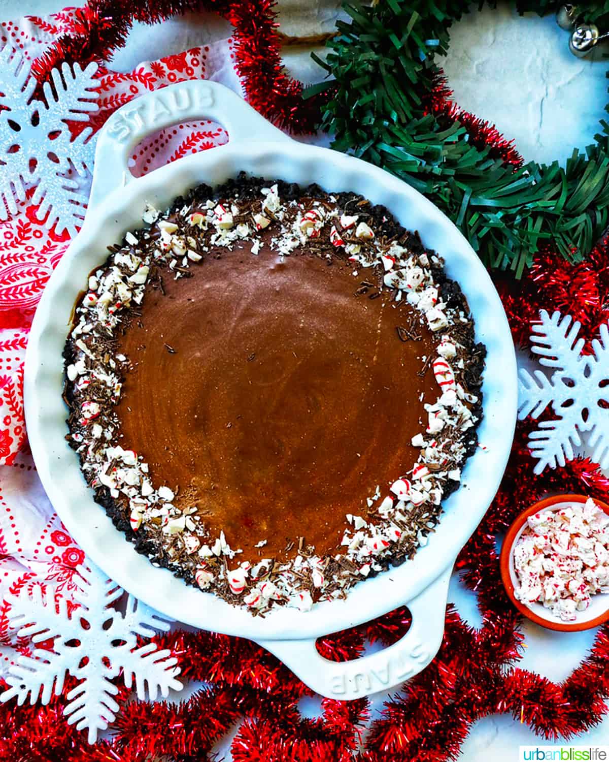 chocolate peppermint pie in a pie plate with side of crushed peppermint candies.