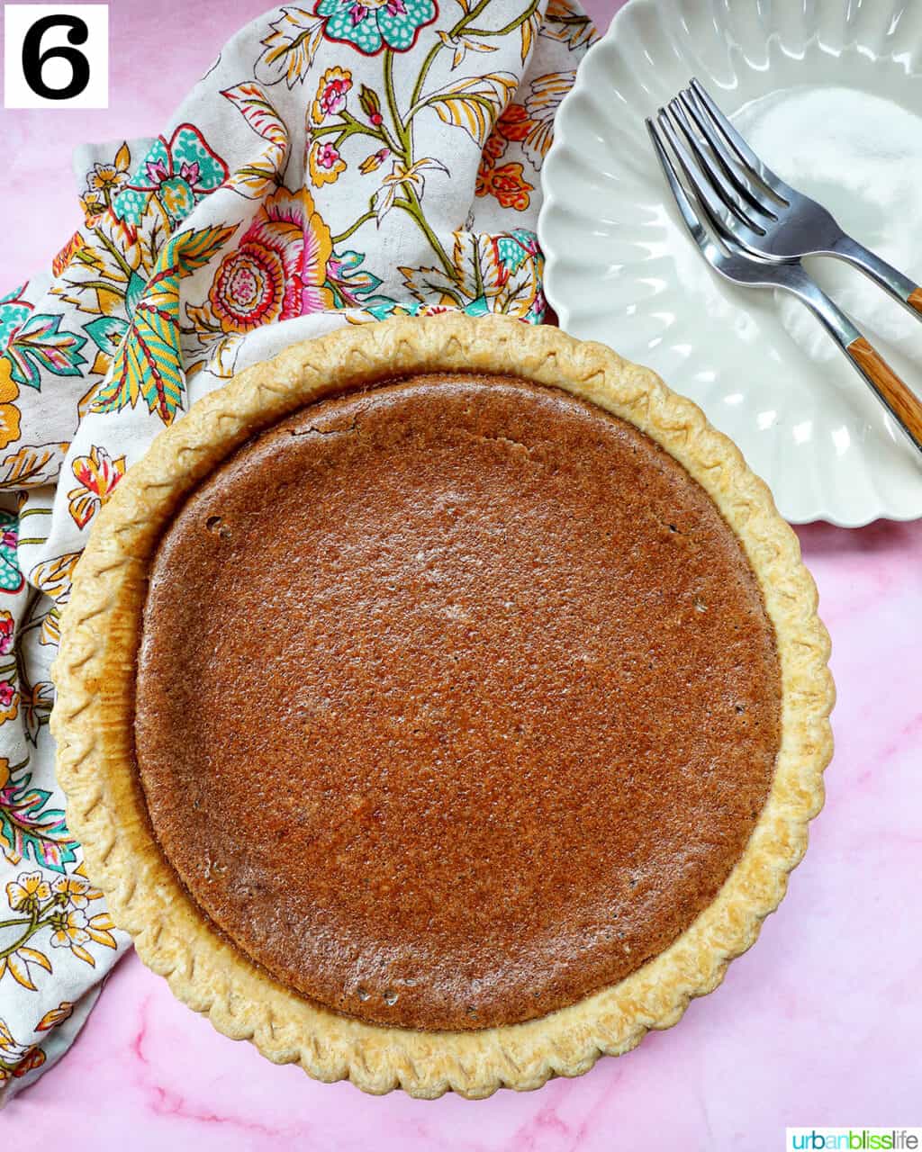 baked cinnamon pie on a pink table with colorful napkin and forks on a plate.
