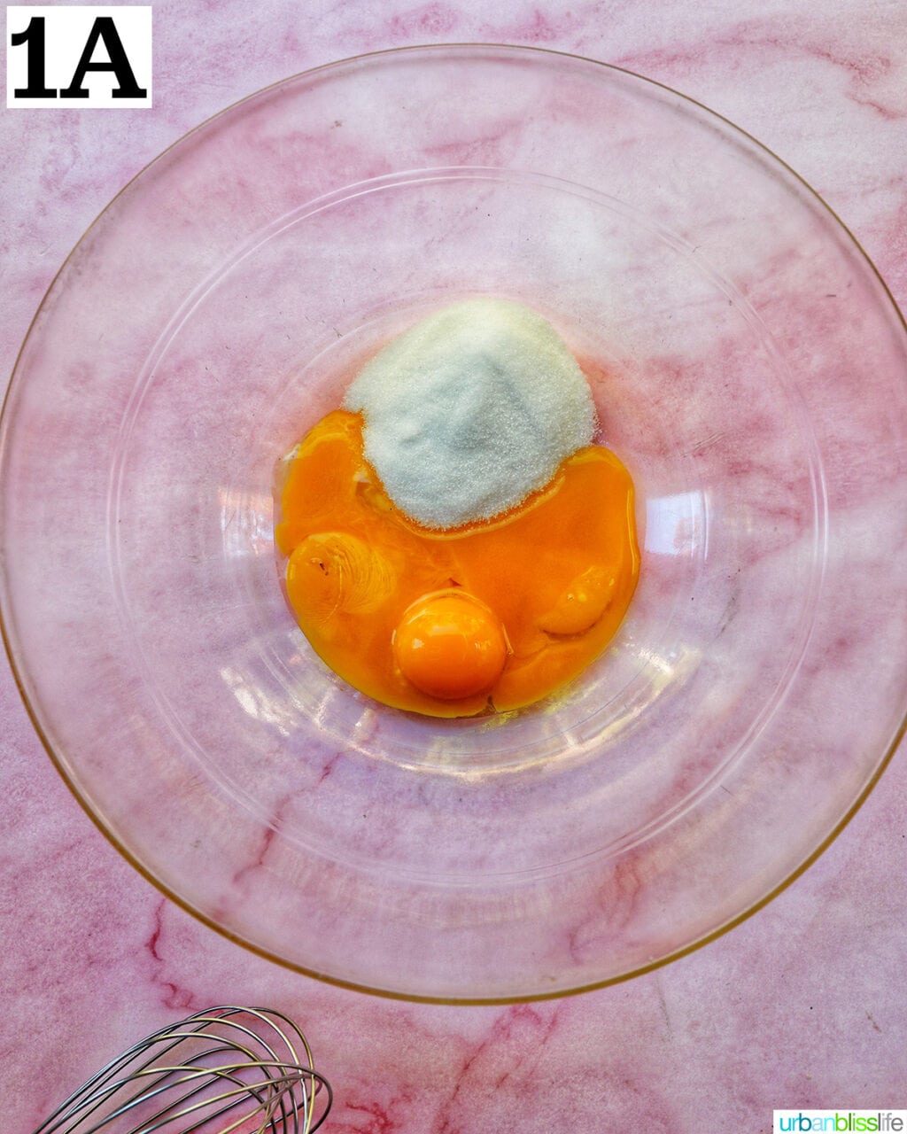 egg yolks and granulated sugar in a clear glass bowl.