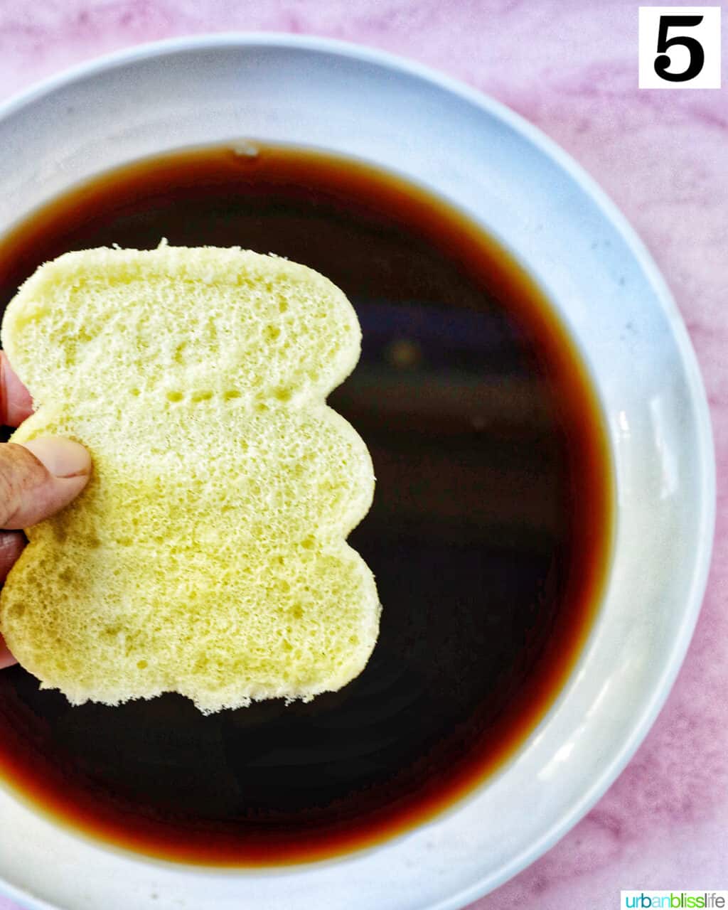hand dipping ladyfinger cookies into a coffee marsala mixture for tiramisu.