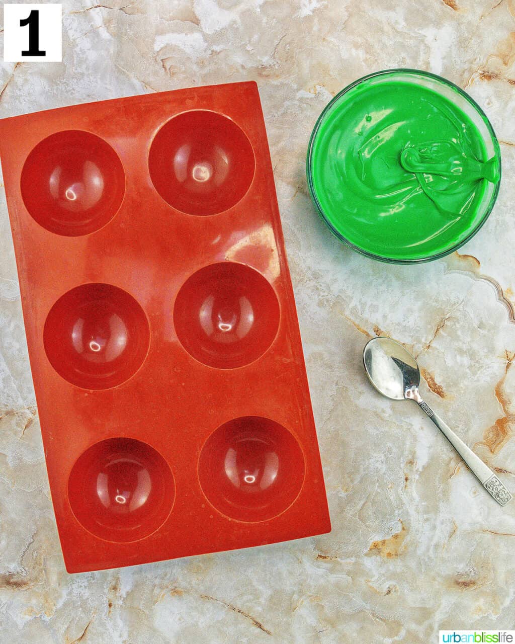chocolate mold with bowl of green melted chocolate and a spoon.