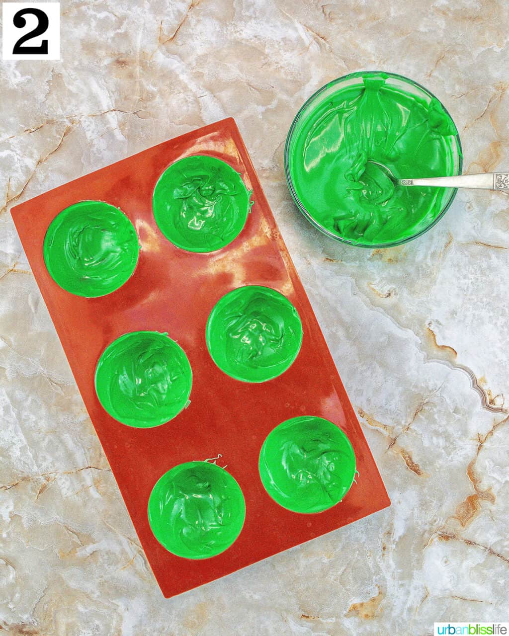 chocolate mold with bowl of green melted chocolate and a spoon.