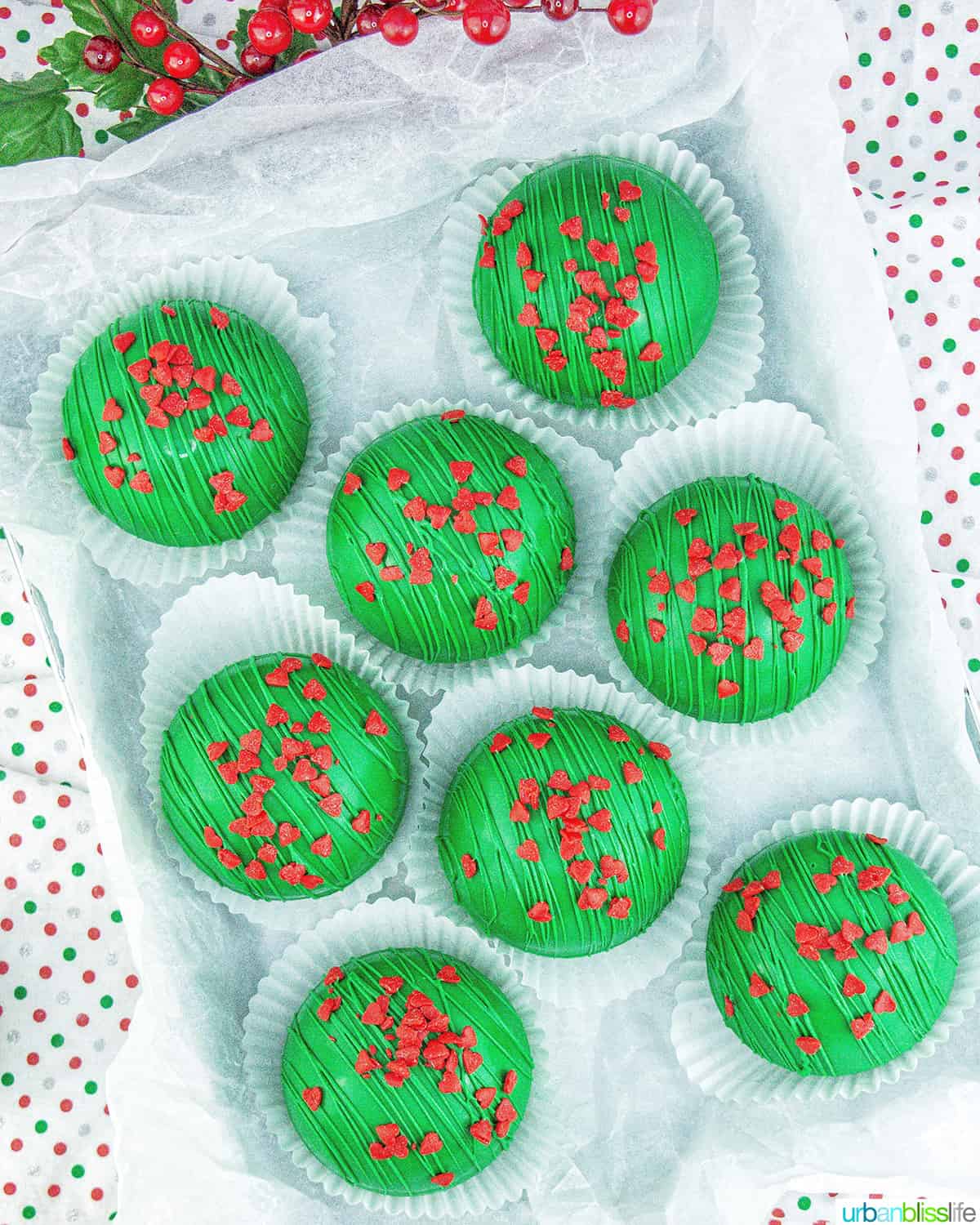 several bright green Grinch hot chocolate bombs with red heart sprinkles.