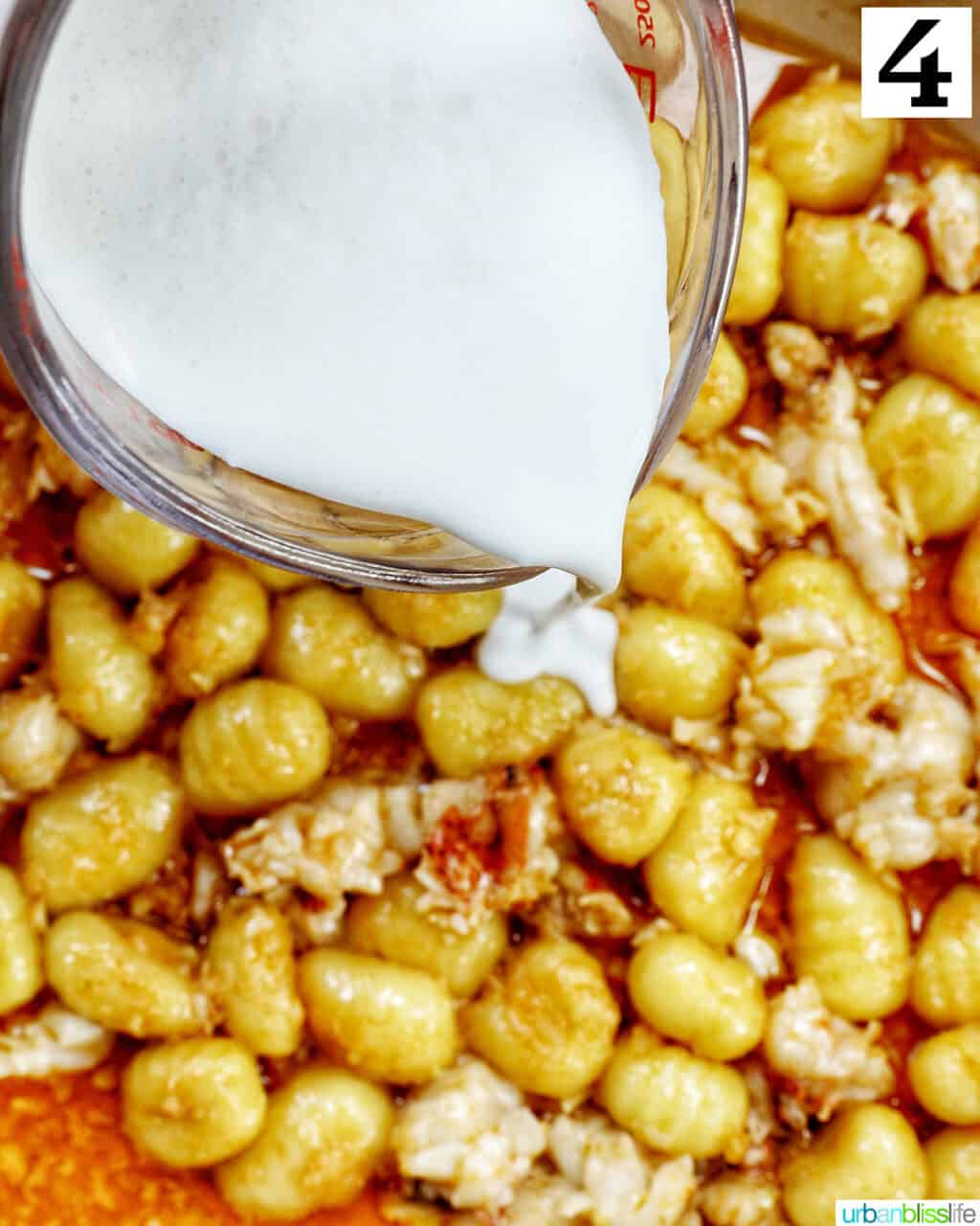 pouring cream over gnocchi in a skillet.