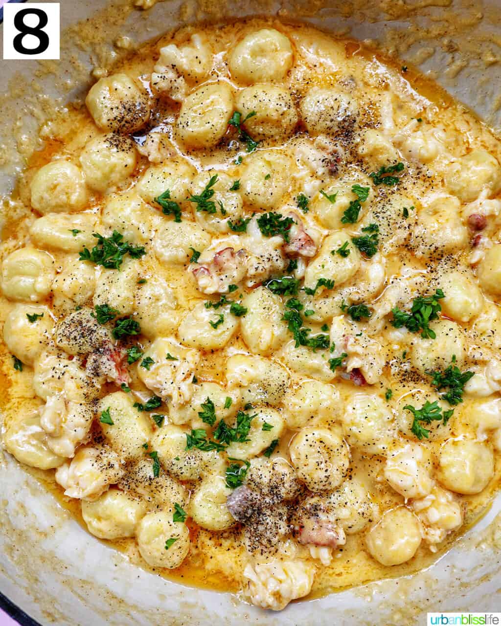 finishing garnishes to lobster gnocchi in a skillet.