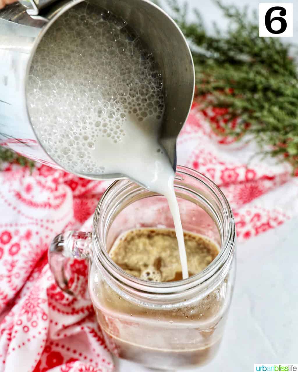 Pouring steamed milk into a mug of white chocolate peppermint mocha.