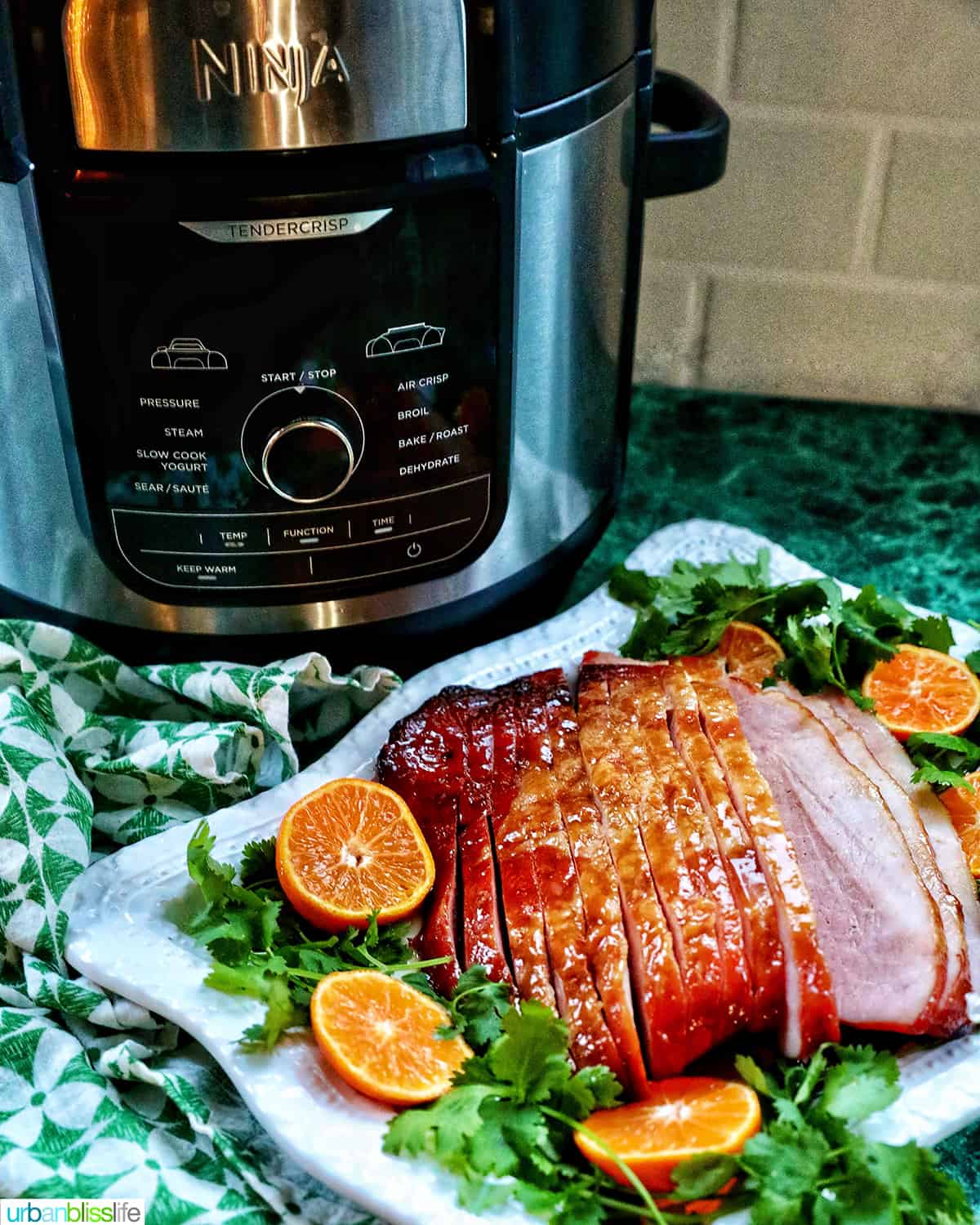 Ninja Foodi air fryer with an air fryer ham plated in front of it.