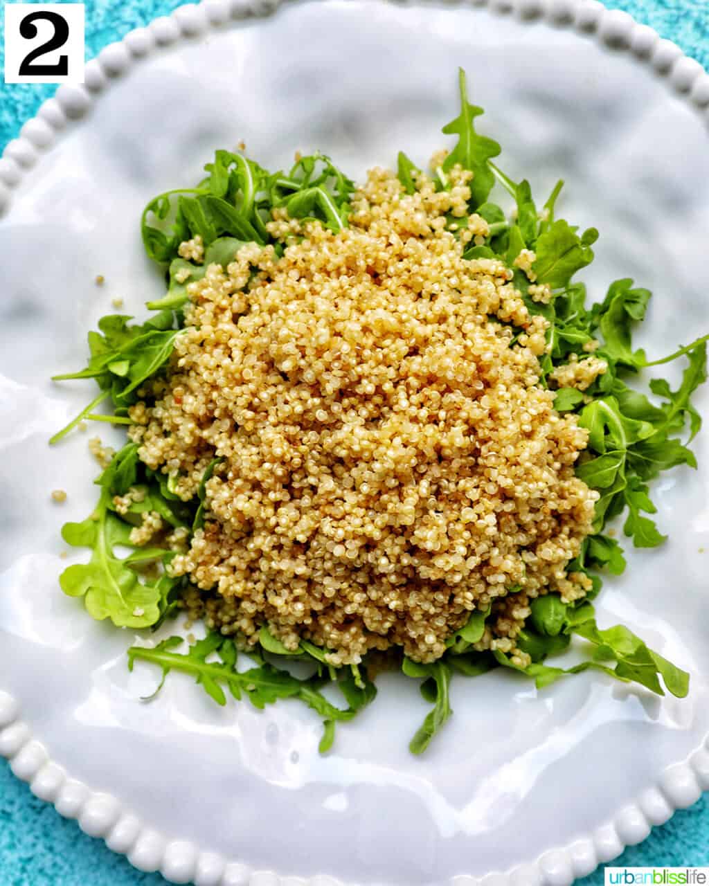 white bowl with arugula and quinoa salad.