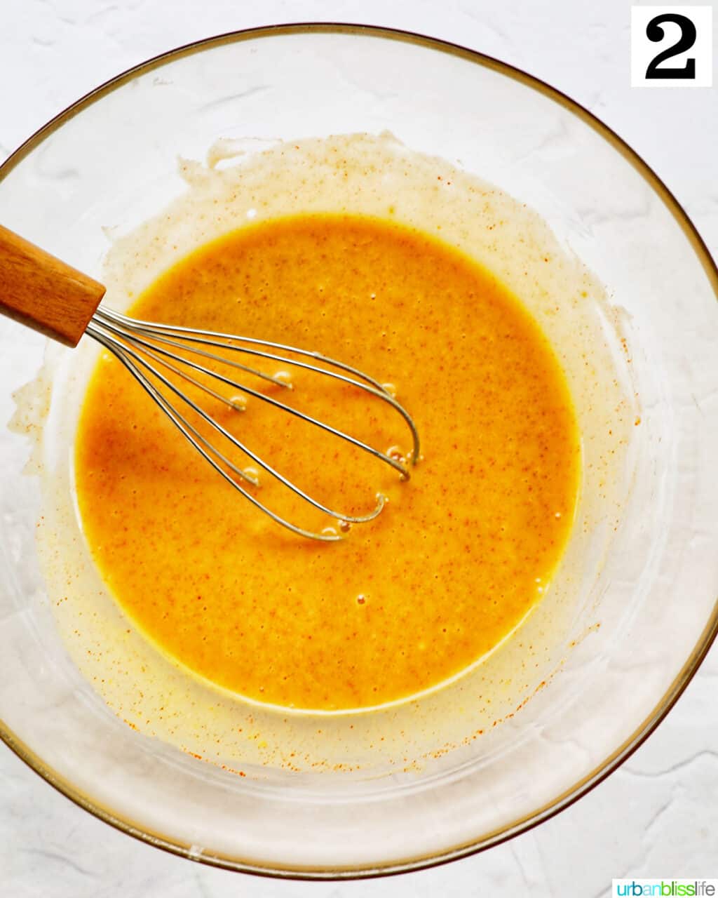 whisk stirring honey mustard sauce in a glass bowl.