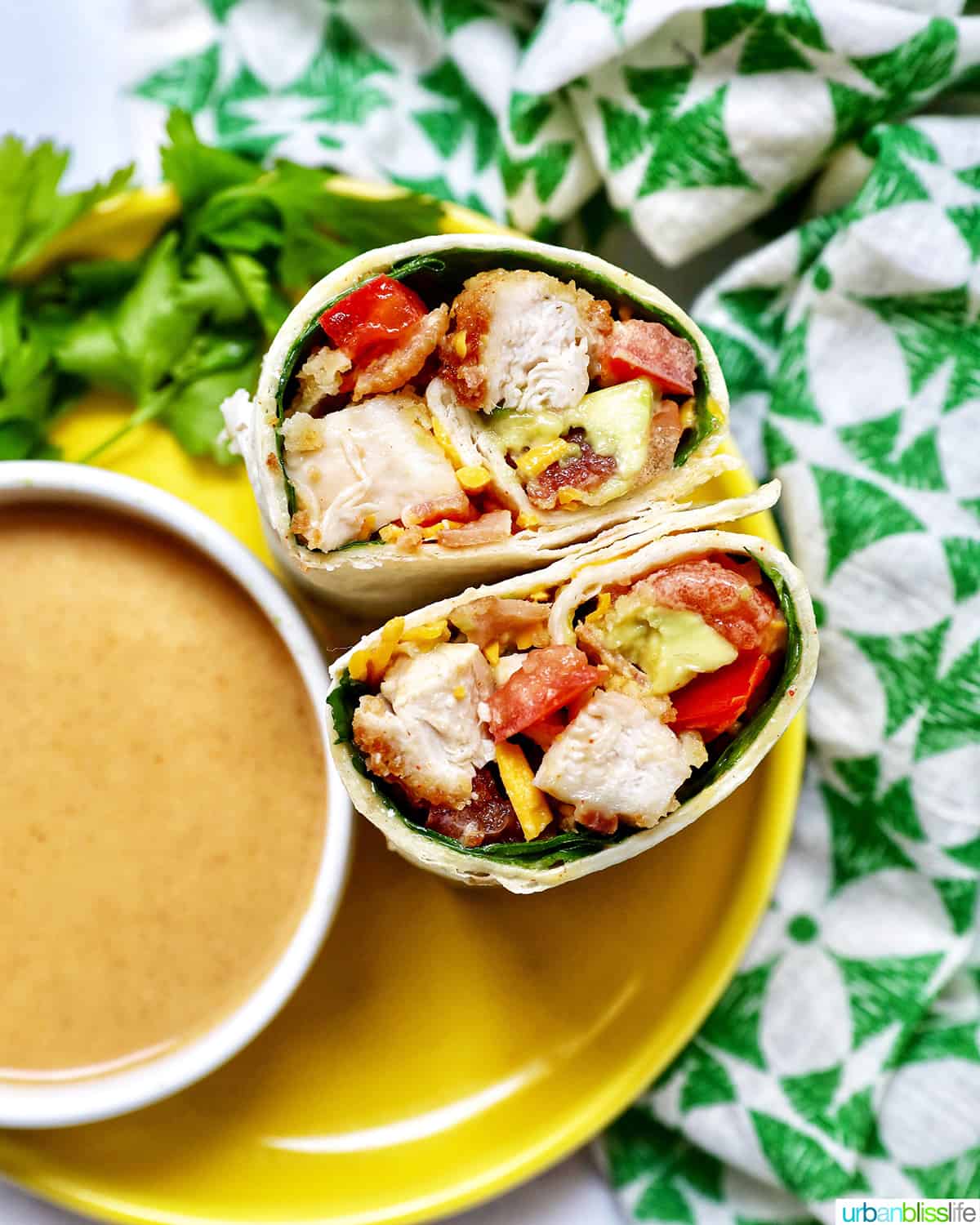 honey mustard chicken wrap cut in half next to a bowl of honey mustard dipping sauce.