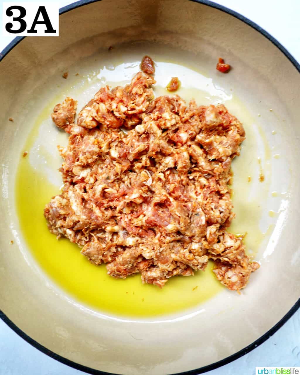 Italian sausage cooking with olive oil in a large skillet.
