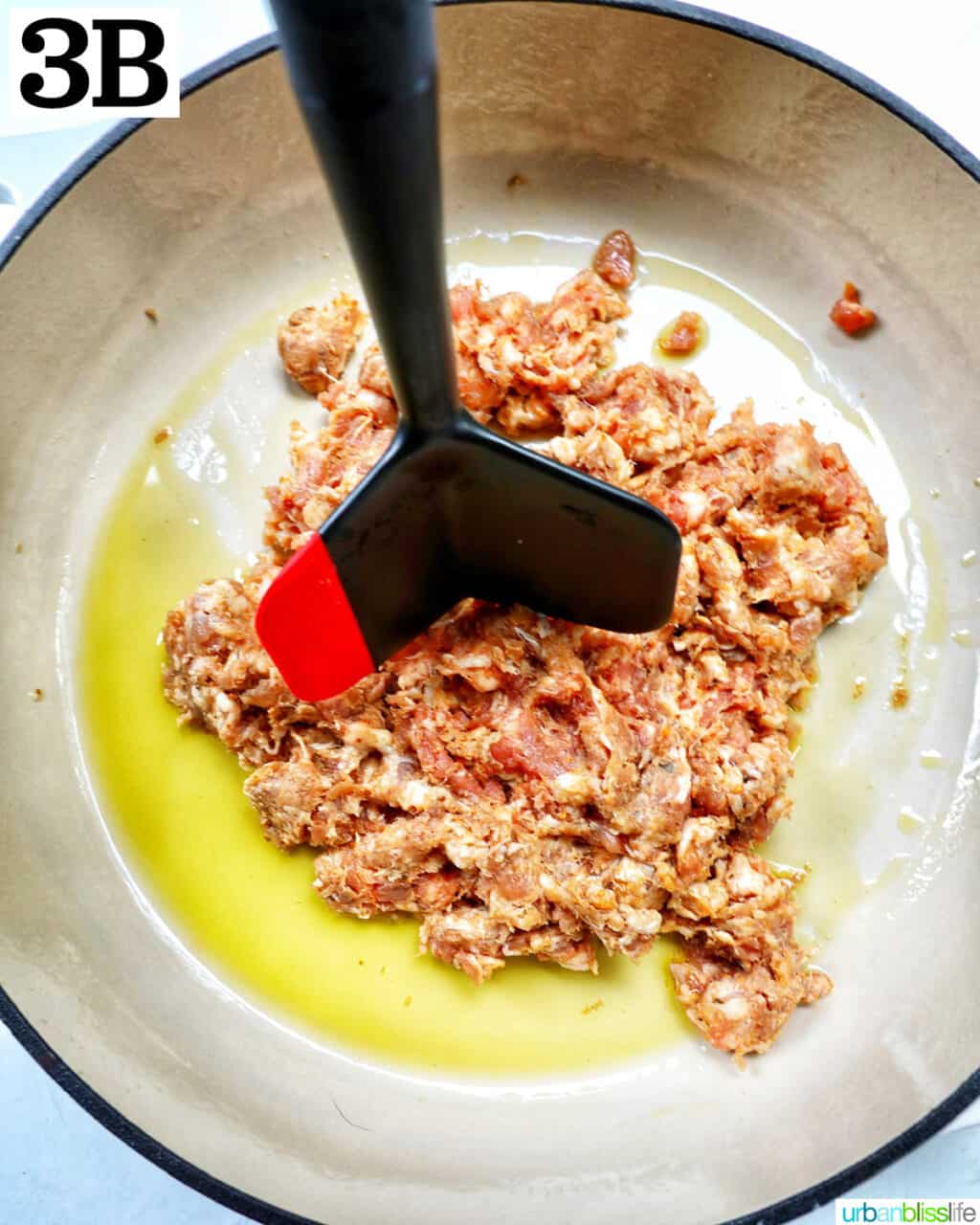 meat chopper chopping up ground italian sausage in a large skillet.