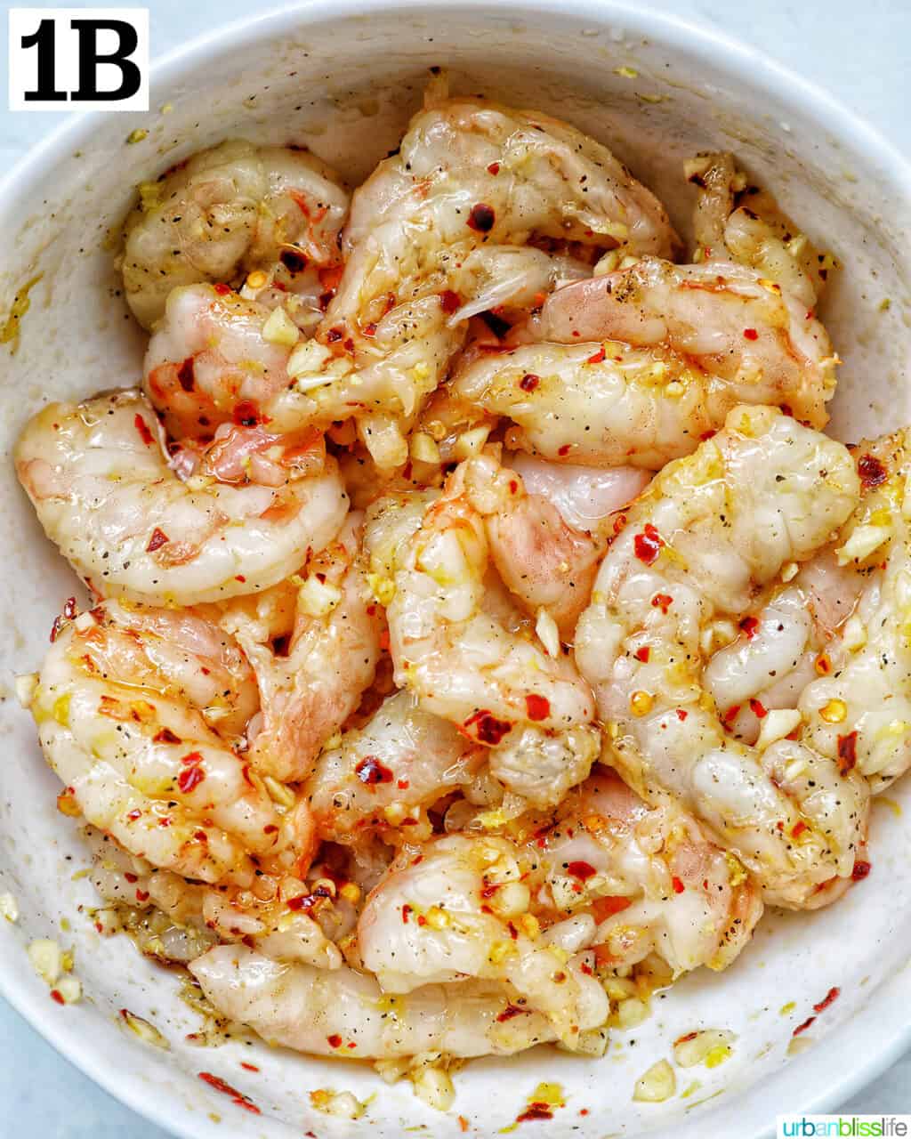 shrimp in a bowl with minced garlic and pepper flakes.