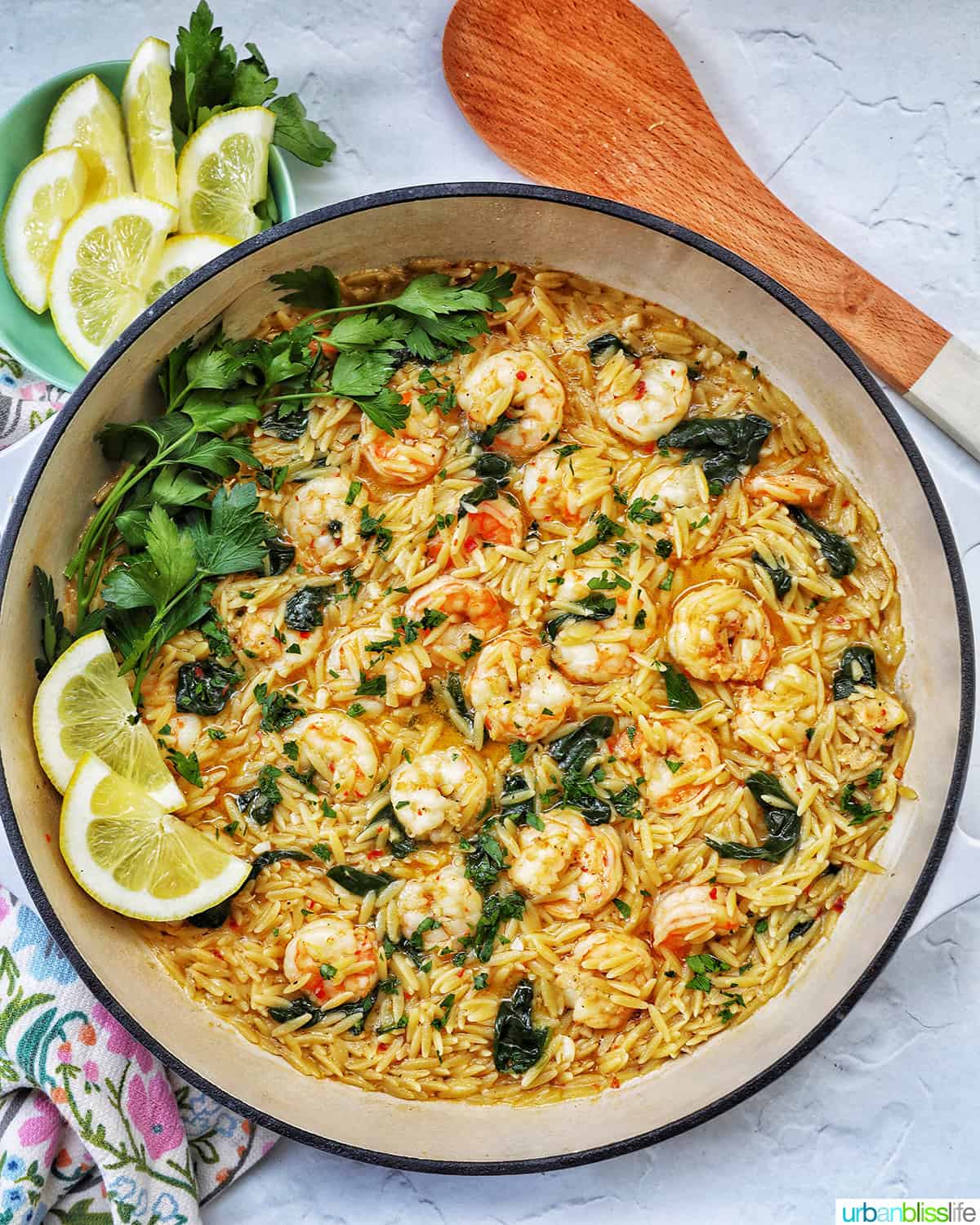 Skillet with shrimp scampi and orzo, lemons, and parsley.