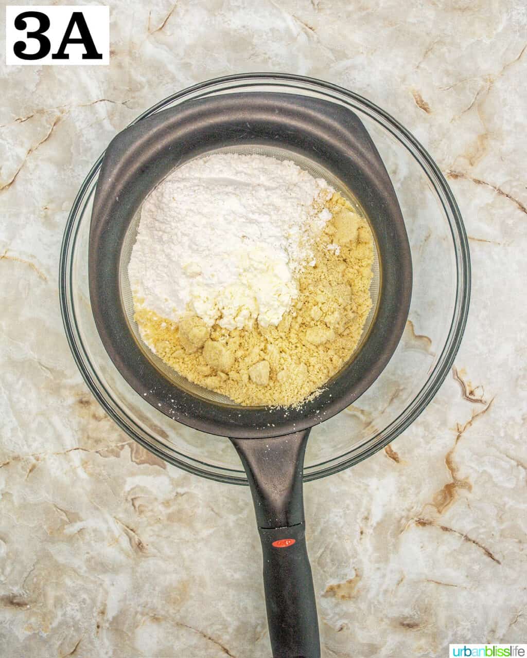 dry ingredients in a strainer over a glass bowl.