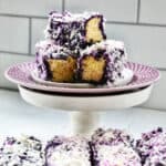 stack of ube bars sliced on a purple plated pedestal with a row of ube bars beneath.