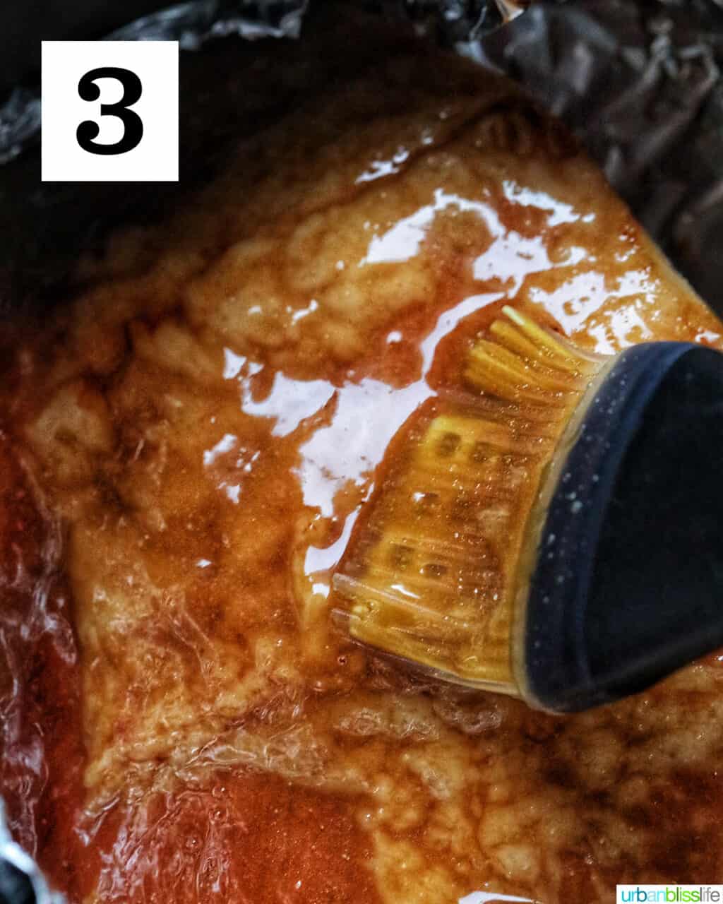 basting brush brushing sweet glaze onto ham in an air fryer.