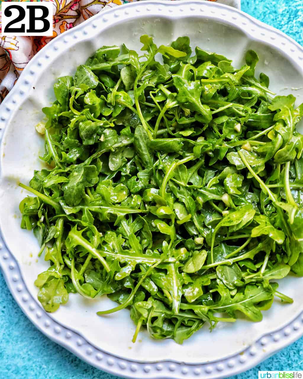 baby arugula in a large white bowl with lemon mustard dressing.