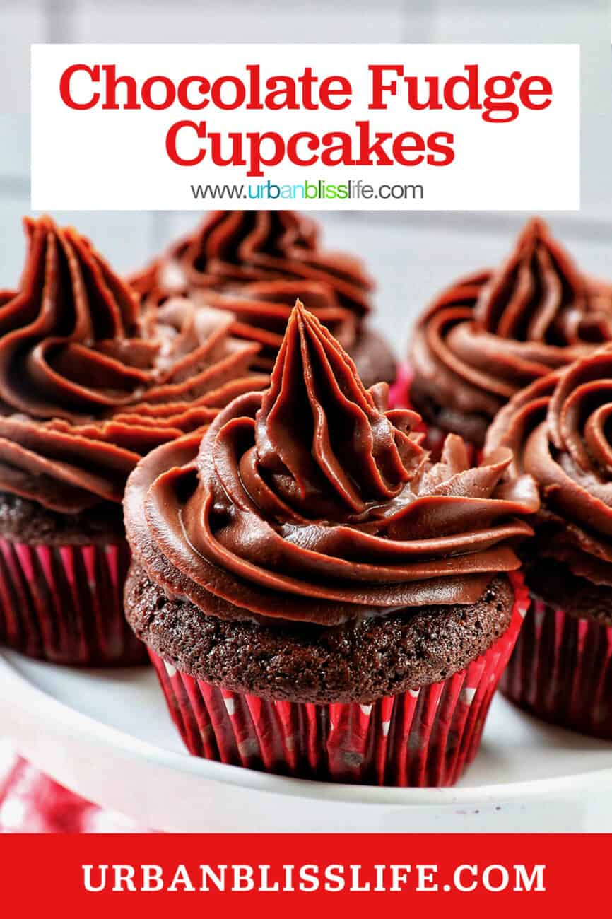 chocolate cupcakes with chocolate fudge frosting stacked on a cake pedestal.