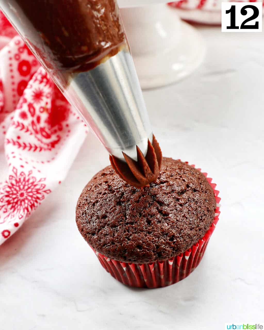 chocolate ganache frosting piping onto a chocolate fudge cupcake.