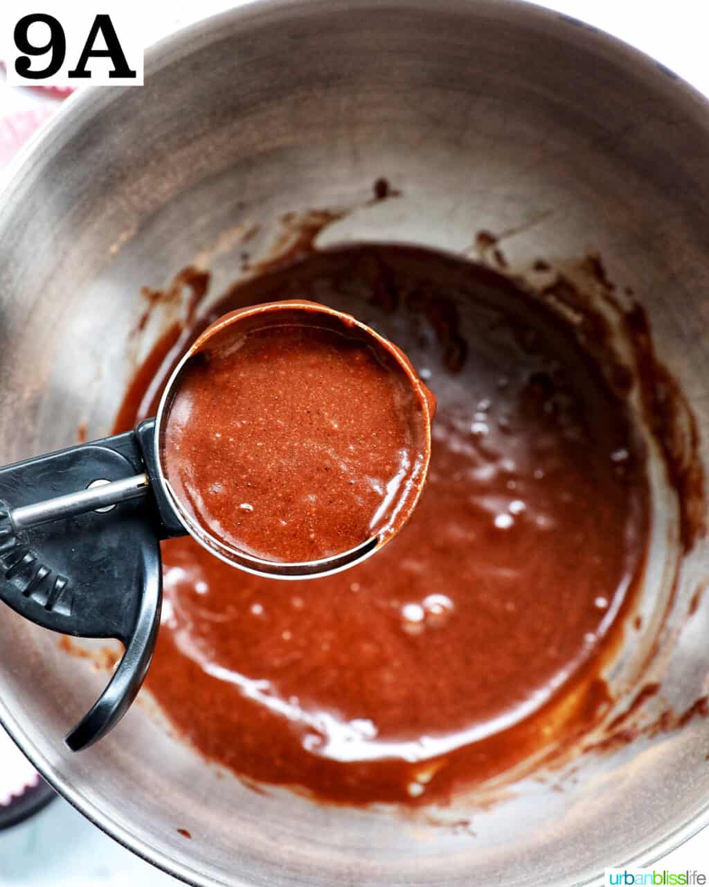 scoop with chocolate fudge cupcake batter over a bowl of batter.