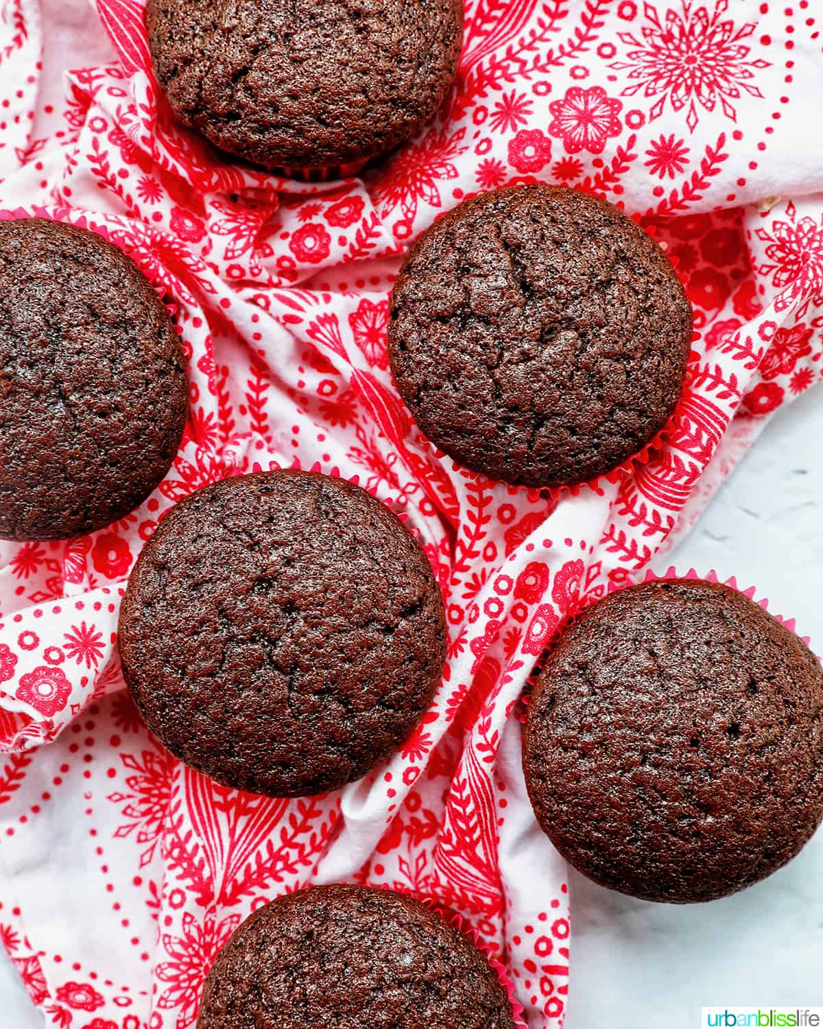 chocolate cupcakes without frosting stacked on a red and white napkin.