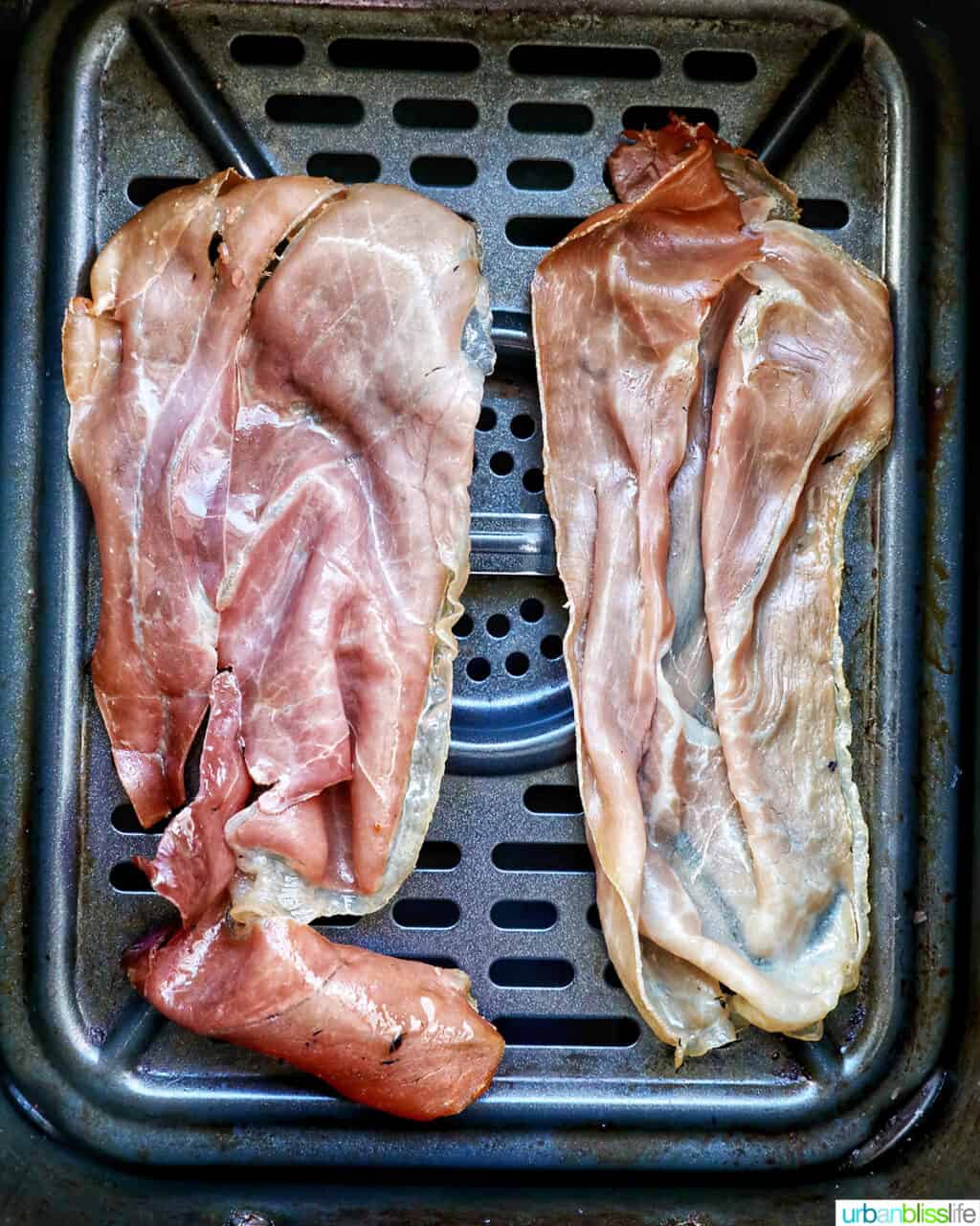 prosciutto strips in an air fryer basket.