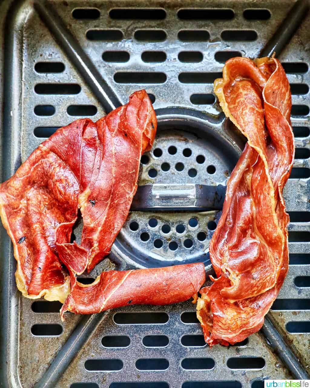 cooked crispy prosciutto in an air fryer basket.