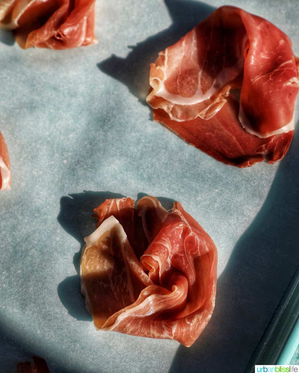 prosciutto on a baking sheet with shadows.